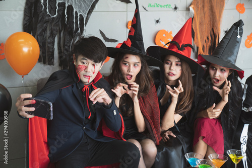 Young Asian people, a group of four persons, in scary costumes selfie their own photo. Group of friends having fun at a party in a nightclub to celebrate Halloween festival.