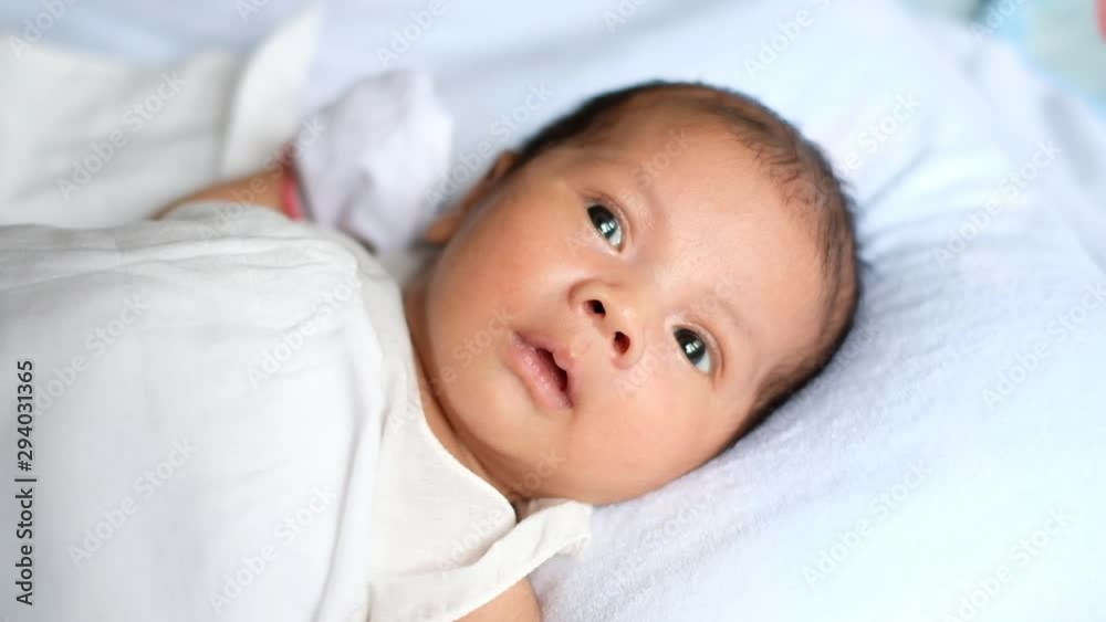 Newborn baby waking up and opening eyes. Lovely asian new born baby. Little baby boy lying on bed. Concept of caring for children and parental love. Newborn baby waking up and opening eyes. Lovely asian new born baby. Little baby boy lying on bed. Concept of caring for children and parental love.