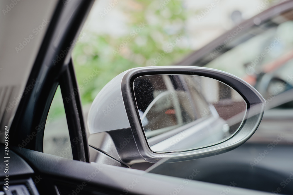 Car side mirror. A mirror in a silver frame view from the center of the car. The concept of using side mirrors, driving safety. Awareness of the driver.
