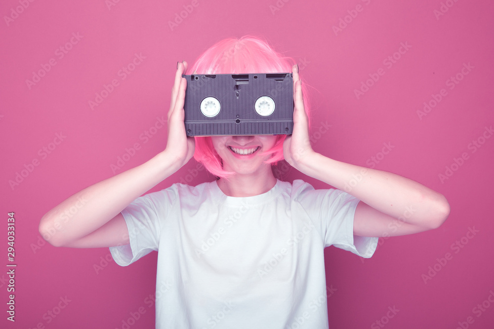 Fototapeta premium Young girl 90s and VHS cassette on pink background.