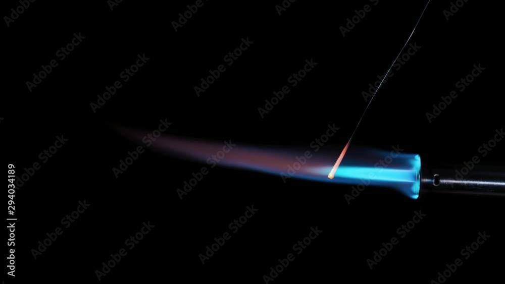 Butane gas burner flame burning from nozzle against black background