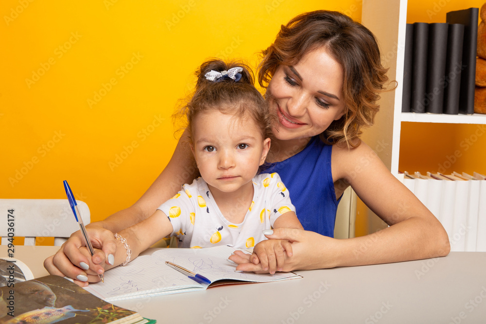 Mother with daughter studying together sitting at the table at home isolated Mother with daughter studying together sitting at the table at home isolated