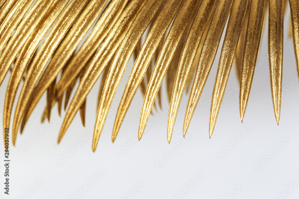 Fototapeta premium Golden colored leaf of palm close up. Painted metallic plants. Creative decoration background with nature pattern and natural texture.