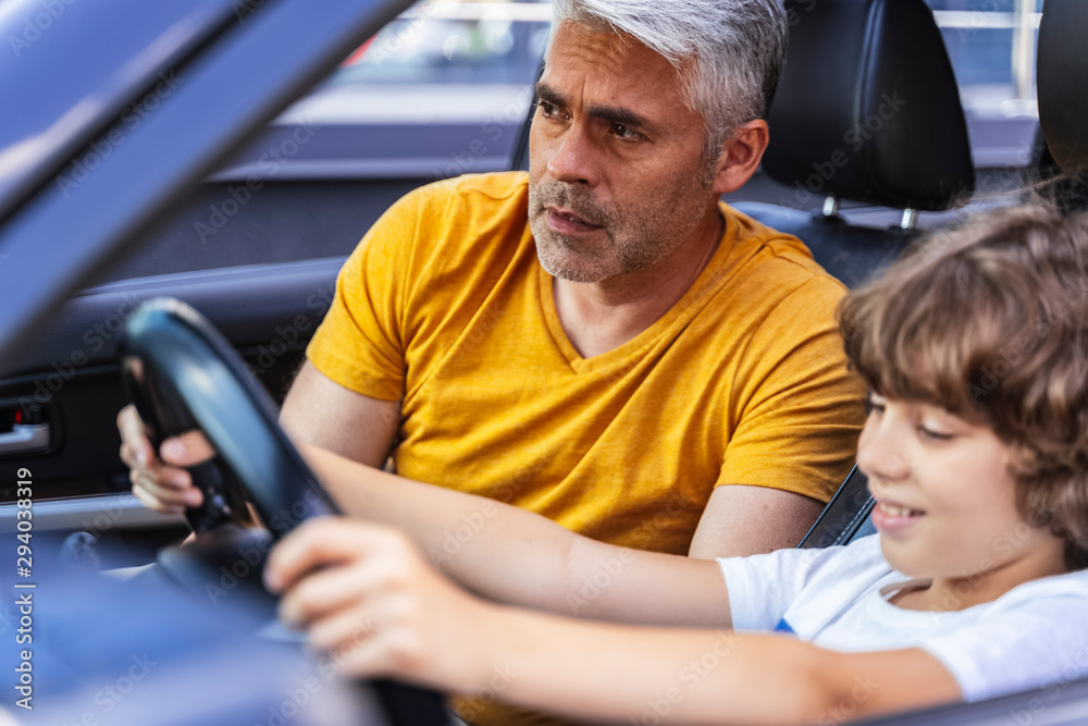 Handsome father teaching his son how to drive vehicle Handsome father teaching his son how to drive vehicle