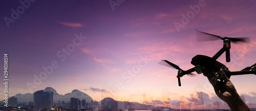 Hnad holding Drone quad copter with high resolution digital camera on the sky mountain and city background.