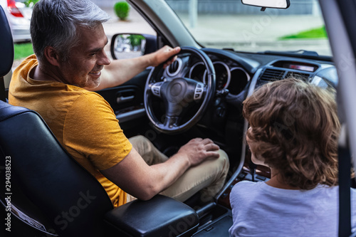 Little boy sitting near his father inside of vehicle