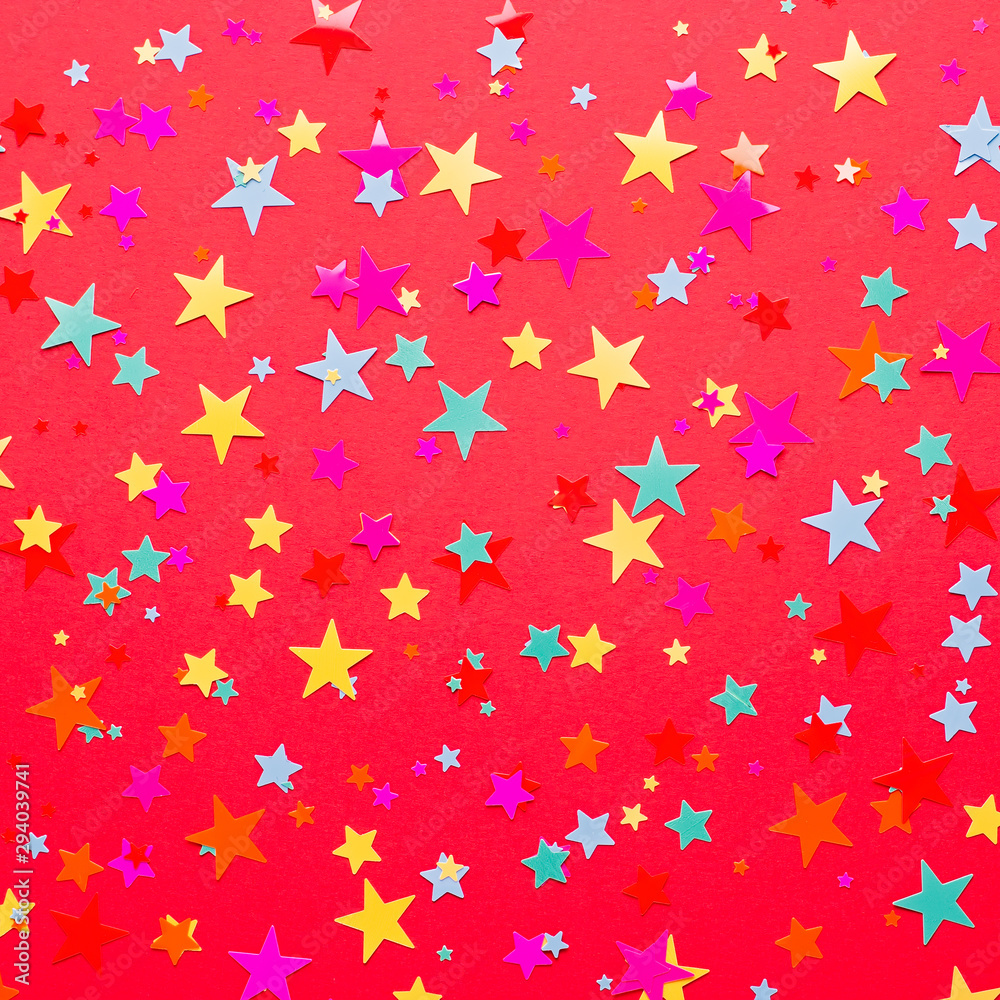 Festive red background with multicolor star confetti and streamers. Background for birthdays, christmas, anniversary. Holiday red background Festive red background with multicolor star confetti and streamers. Background for birthdays, christmas, anniversary. Holiday red background