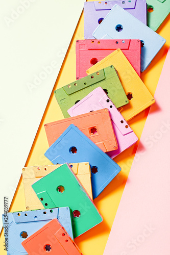 Painted audio cassettes in pastel colors on bright multicolor background, copy space, top view. Retro musical background