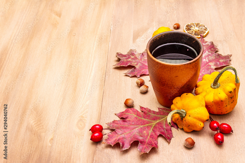 Autumn cozy mood composition. Hot tea in ceramic glass, fall leaves, pumpkins, briar, hazelnuts Autumn cozy mood composition. Hot tea in ceramic glass, fall leaves, pumpkins, briar, hazelnuts
