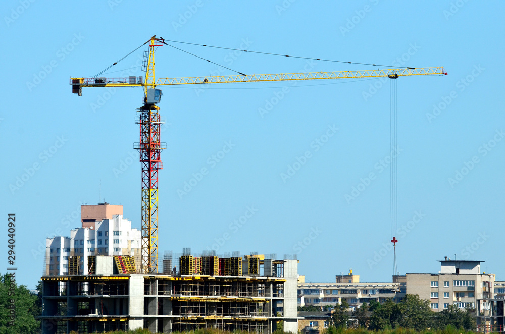 Tower cranes constructing a new residential building at a construction site against blue sky. Renovation program, development, concept of the buildings industry. Tower cranes constructing a new residential building at a construction site against blue sky. Renovation program, development, concept of the buildings industry.