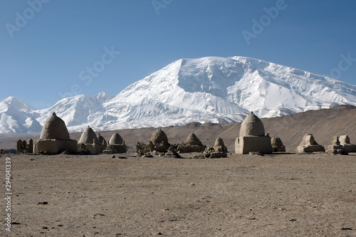 Mountainous landscape. Old kyrgyz cemetery on the background of Muztagh Ata mountain (7546 m). Pamir mountains, outskirts of Kashgar, Xinjiang, China, Asia.