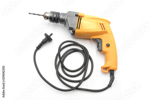 Household yellow electric drill and wire plug closeup isolated on white background