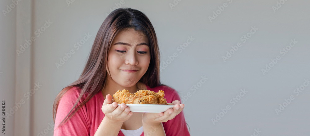 Copy space. Asian young pretty woman slim body smiling and holding delicious crispy fried chicken on dish in kitchen at home, junk food, unhealthy food, dieting, weight loss, good healthy concept Copy space. Asian young pretty woman slim body smiling and holding delicious crispy fried chicken on dish in kitchen at home, junk food, unhealthy food, dieting, weight loss, good healthy concept