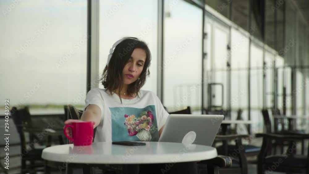 Young female student with headphones in a cafe working with notebook Young female student with headphones in a cafe working with notebook