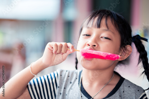 Beautiful asian little girl eats ice-cream in the summer at home