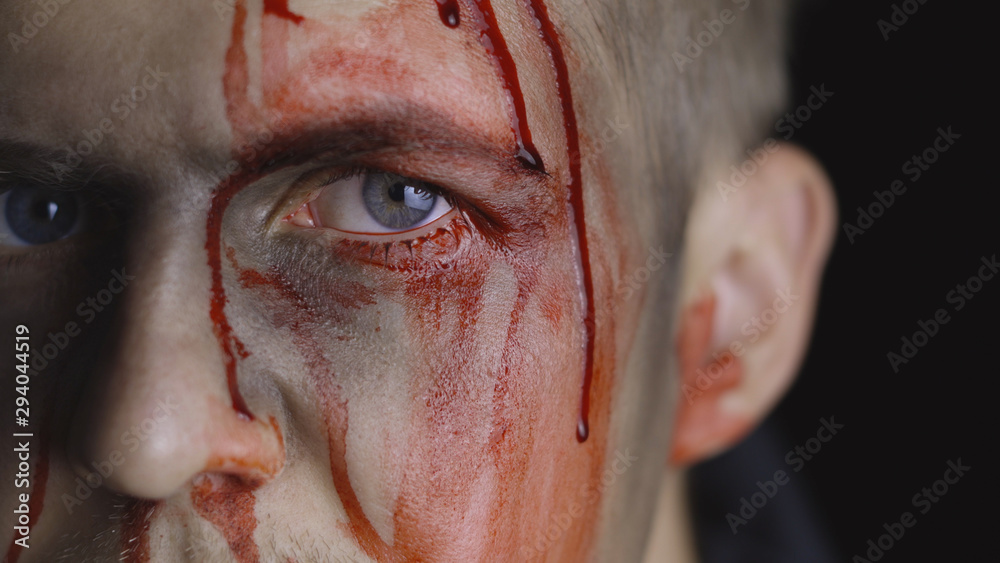 Obraz premium Halloween man portrait. Guy with dripping blood on his face. Scary makeup