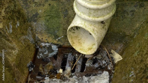 Dirty drain in the rain with debris and fat