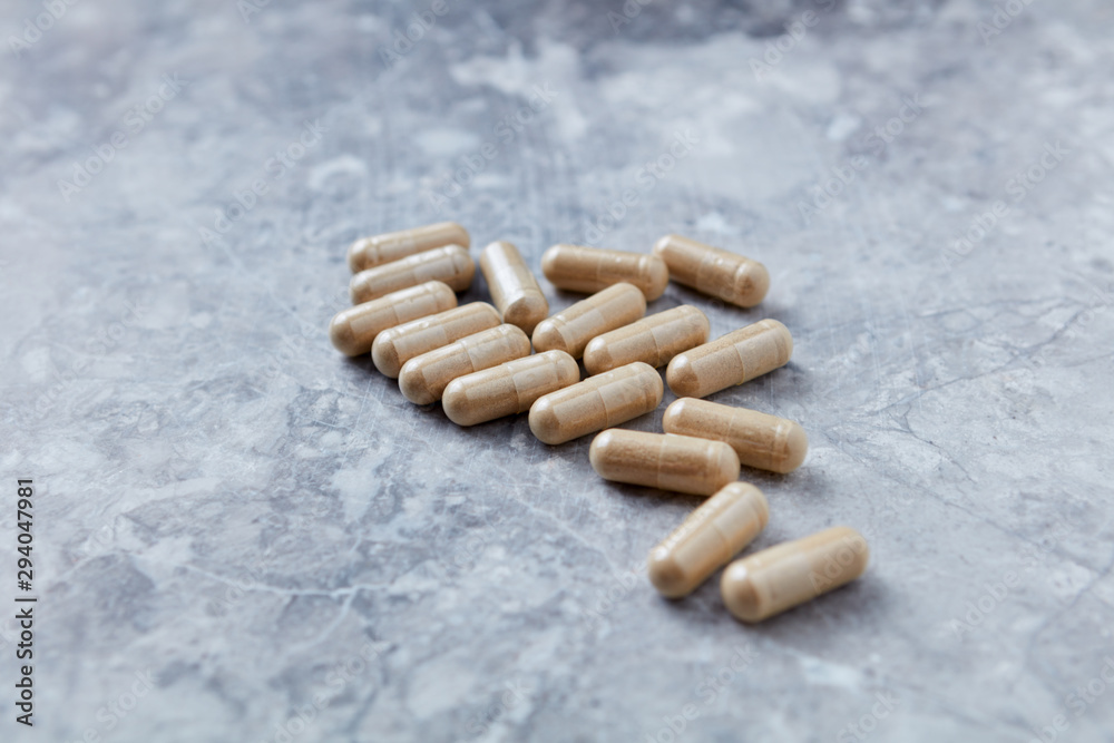 Ashwagandha (Withania somnifera) capsules. Concept for a healthy dietary supplementation. Bright stone background. Copy space. 