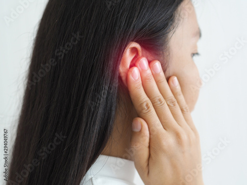 ruptured eardrum,tinnitus and meniere disease and otitis media in asian woman. She use hand touching her ear causes of ear pain on white background use for health care concept. photo