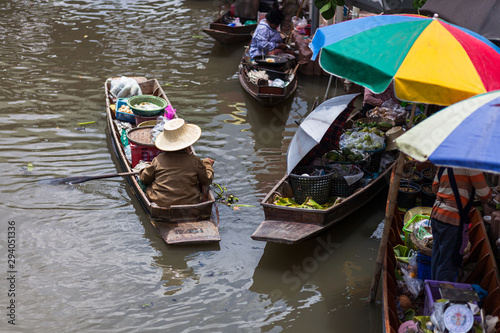 Asian womenin an old wooden canoe on amphawa floating market in thailand near bangkok. Boat is full of food, groceries and other salesman stuff. © benschie