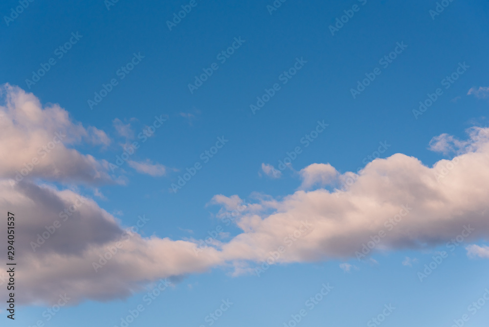 Crisp and clean nature background cumulus clouds in evening light, blue sky and white clouds