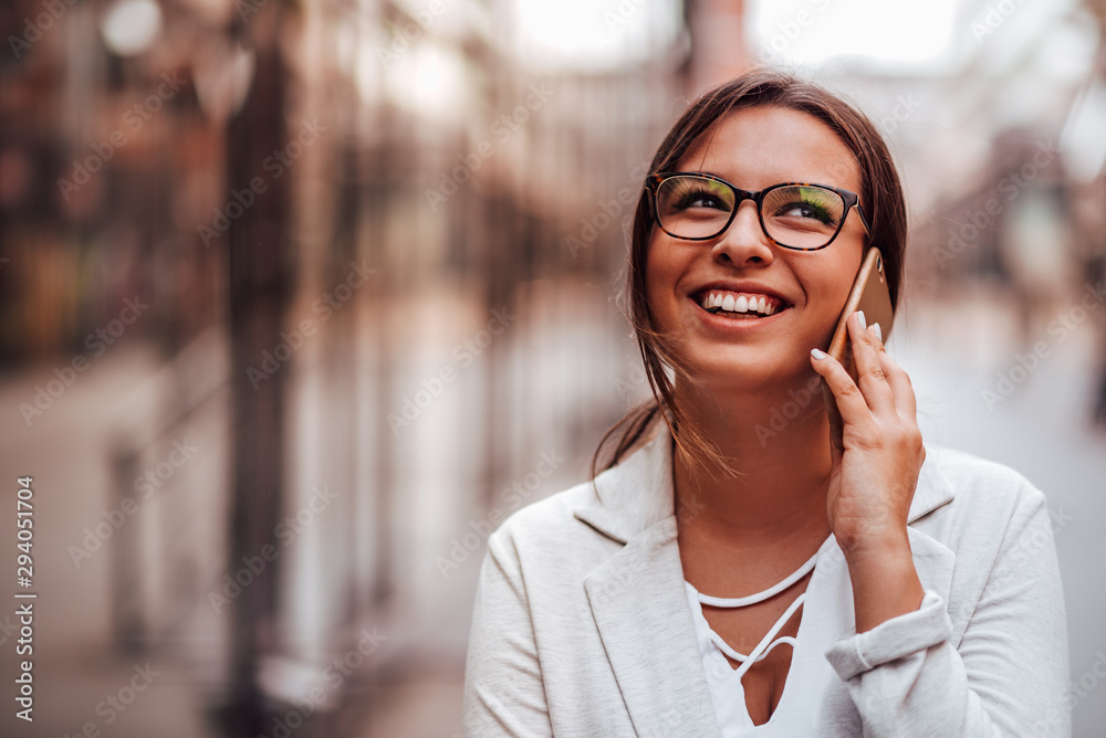 Portrait of a happy young woman talking on mobile phone outdoors in the city, focus on the girl, copy space. Portrait of a happy young woman talking on mobile phone outdoors in the city, focus on the girl, copy space.
