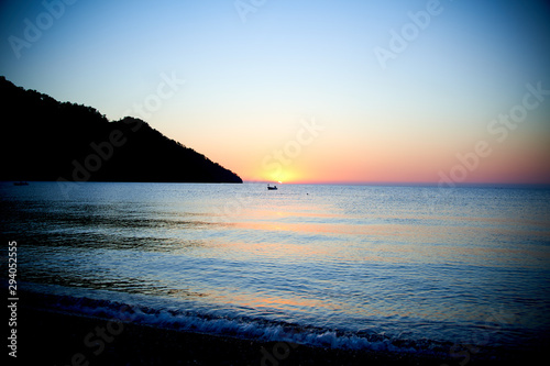 Orange sunset above sea with boat amazing Golden reflection of the sun on the calm waves