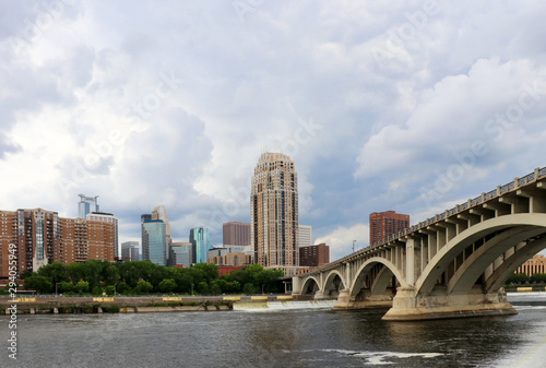 Urban cityscape and modern architecture background. Cloudy sky over Minneapolis downtown skyline and Third Avenue Bridge above Mississippi river. Midwest USA, Minnesota.