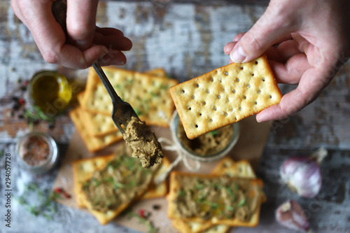 Fototapeta Naklejka Na Ścianę i Meble -  Male hands put the home liver pate on a cracker with a fork. Delicious homemade pate with spices and herbs. Keto diet. Healthy food. Selective focus. Macro.