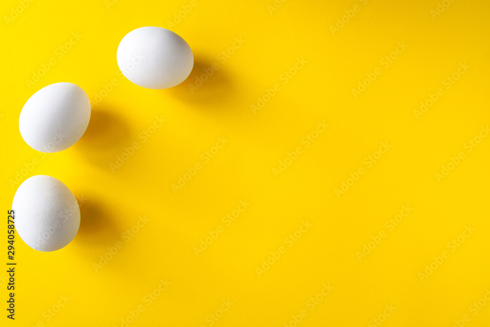 Three white eggs on a yellow background. International world egg day...