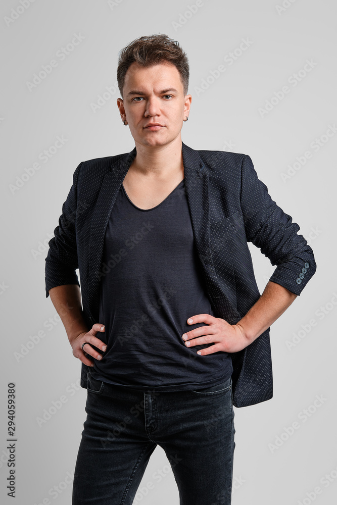 Portrait of serious man in jeans, t-shirt and fitted jacket with hands on waist Portrait of serious man in jeans, t-shirt and fitted jacket with hands on waist