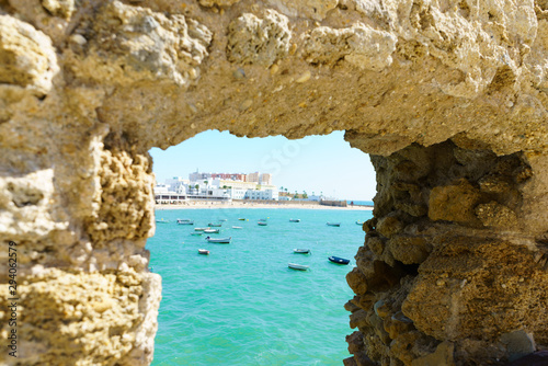 Window in stone medieval fortress with view at Cadiz beach, Spain, Andalusia