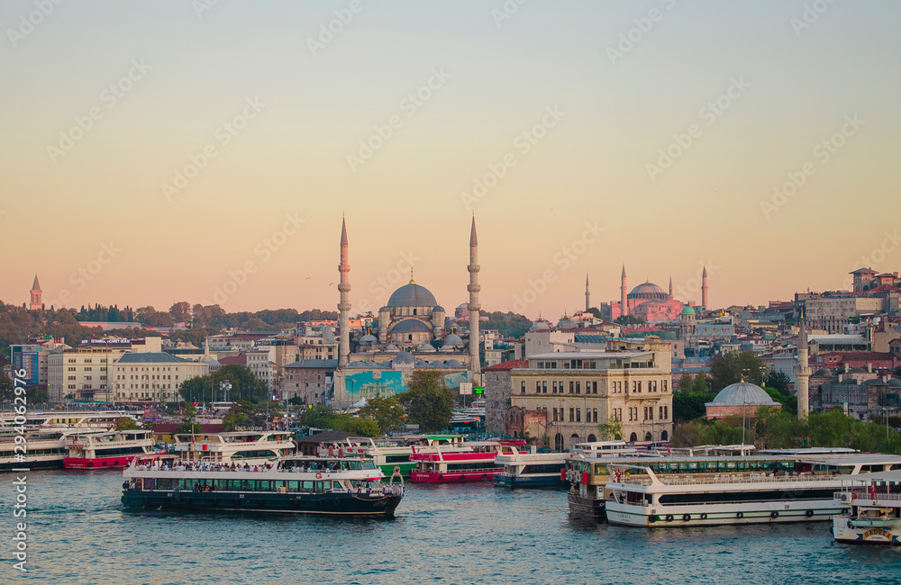 Sunset sky. Tourist pleasure boats on pier in Golden Horn Bay. View of famous Hagia (Aya) Sofia Museum and the New Mosque. Popular tourist destination. Turkey, Istanbul, Bosphorus