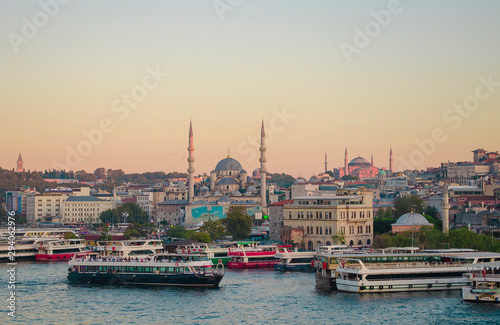Sunset sky. Tourist pleasure boats on pier in Golden Horn Bay. View of famous Hagia (Aya) Sofia Museum and the New Mosque. Popular tourist destination. Turkey, Istanbul, Bosphorus
