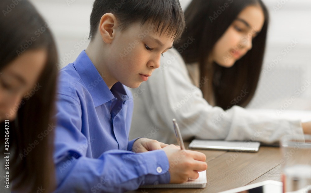 Children writing in copybooks during lesson in classroom Children writing in copybooks during lesson in classroom