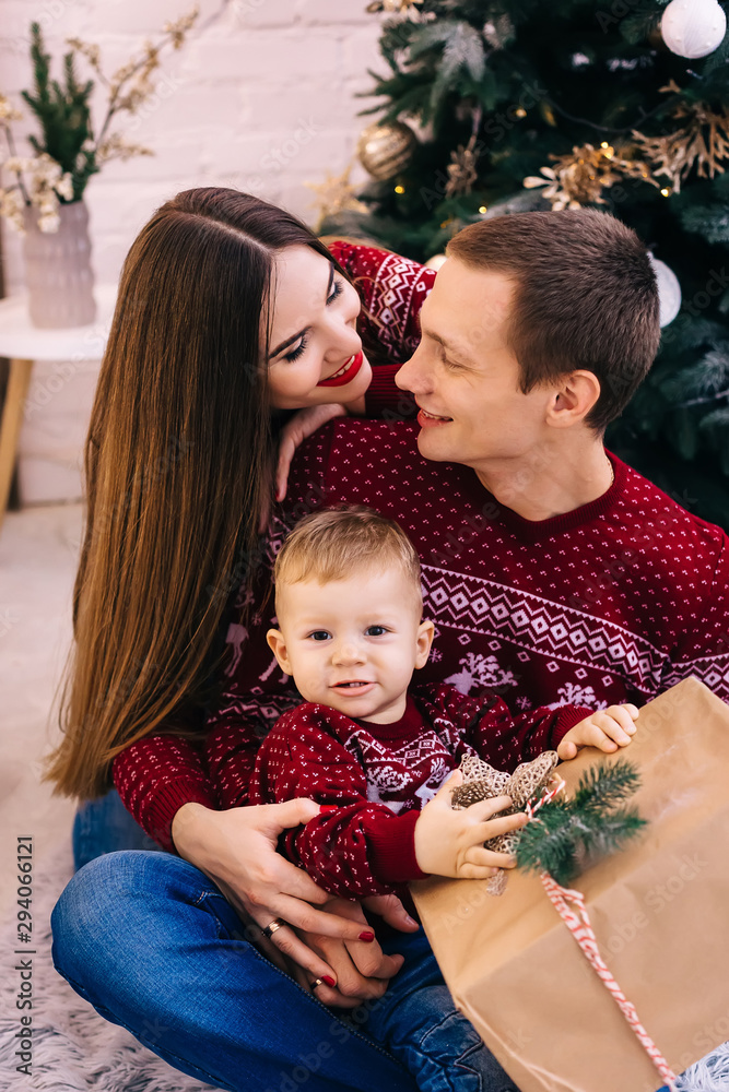 closeup of little boy holding gift and parents embrace him. fami