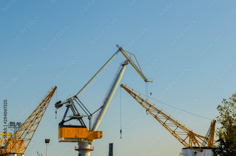 Yellow construction cranes close-up. Blue sky and white clouds. Place for text. Selective focus image. Copy space.