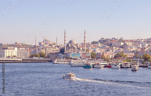 Touristic boats in Golden Horn bay of Istanbul and view on Suleymaniye mosque. View of old city  mosque  red tile roofs and green trees. Clear blue sky. Turkey  Istanbul