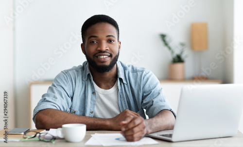 Smiling african american worker looking at camera, sitting at workplace