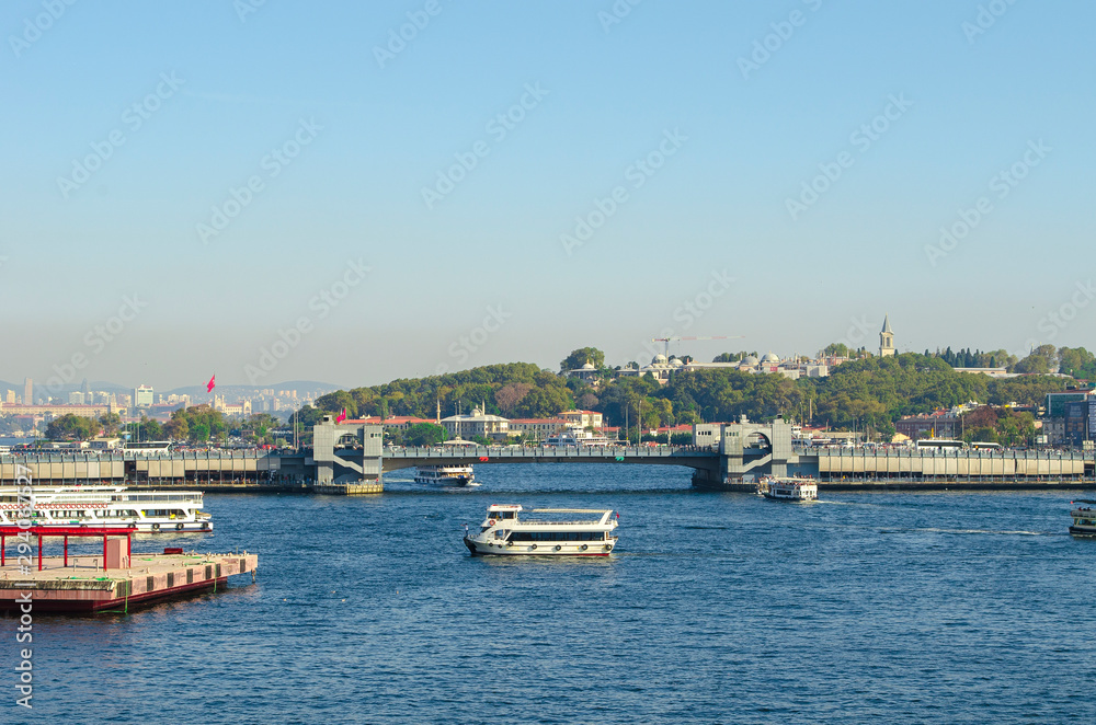 Touristic boats in Golden Horn bay and view on Galata bridge and Suleymaniye mosque. View of old city, mosque, red tile roofs and green trees.  Popular destination. Turkey, Istanbul 