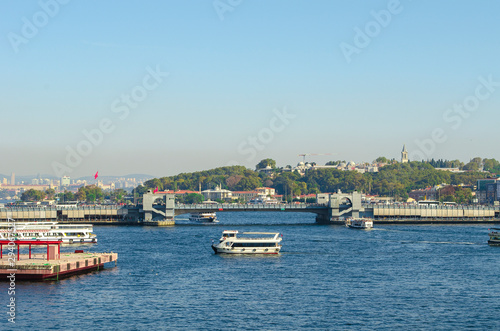 Touristic boats in Golden Horn bay and view on Galata bridge and Suleymaniye mosque. View of old city, mosque, red tile roofs and green trees.  Popular destination. Turkey, Istanbul 