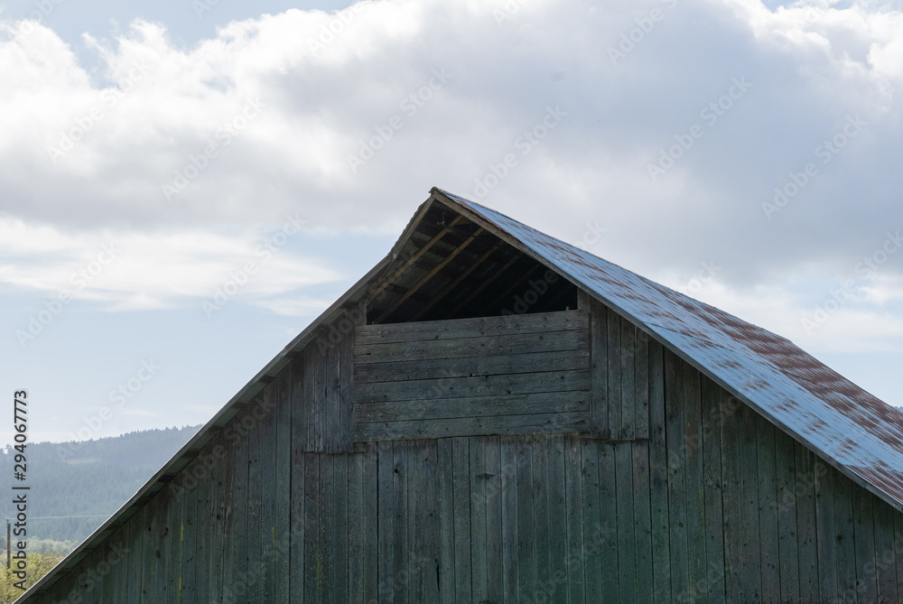 Peak of an old barn against a cloudy blue sky Peak of an old barn against a cloudy blue sky