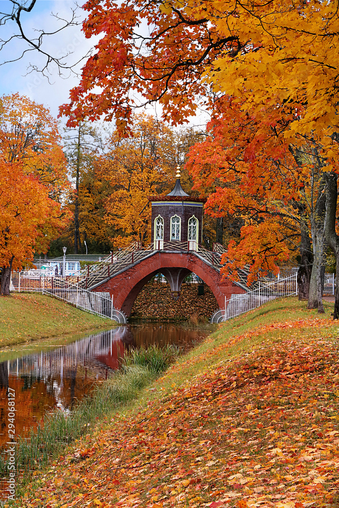 Russia, St. Petersburg, October 5, 2019, Alexander Park. In the photo - an autumn pond with fallen leaves and the Cross Bridge. The beauty of the October forest in Russian forests