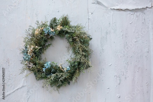 modern Christmas wreath. stylish rustic christmas wreath with pine cones,fir branches,snow, hanging on white wall. space for text. handmade decor for winter holidays