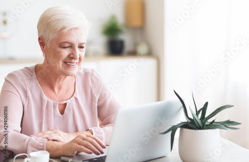 Smiling senior business lady looking at laptop