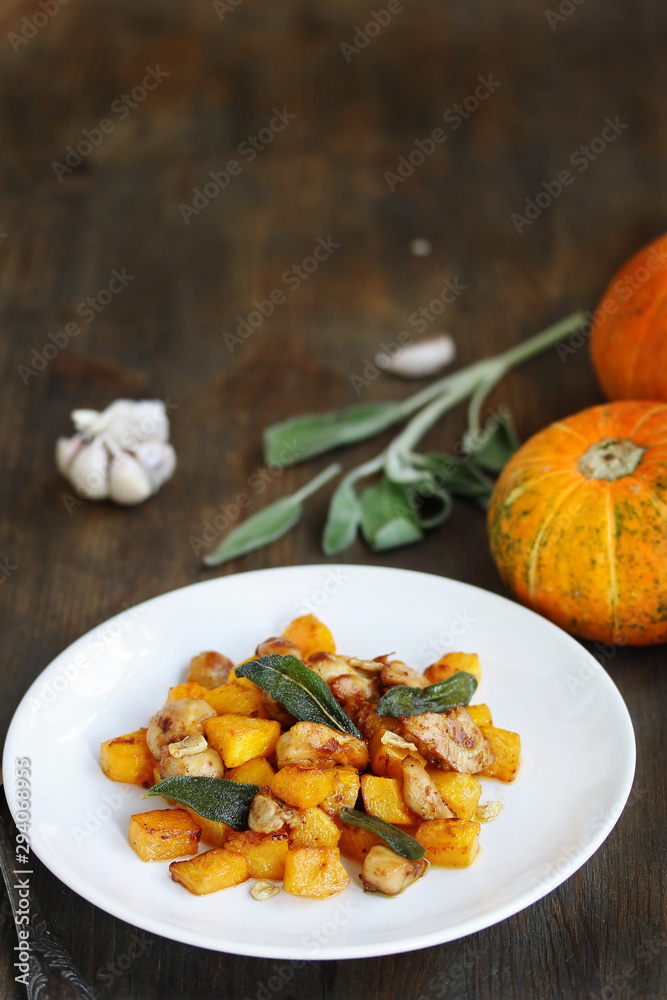 dish with pumpkin. fried chicken fillet and pumpkin cubes with sage (chips from sage). a dish on the table on a sunny day. autumn dish with pumpkin.