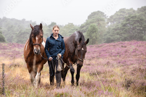 Mädchen wandert mit Pferden durch die Heide