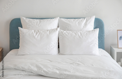 White pillows and duvet on the blue bed. White pillows, duvet and duvet case on a blue bed. White bed linen on a blue sofa. Bedroom with bed and bedding and poster frame mock up on the wall.Front view