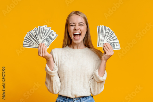 Happy teenage girl holding lots of money and shouting photo