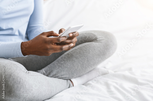 Cropped image of girl using smartphone  sitting on bed